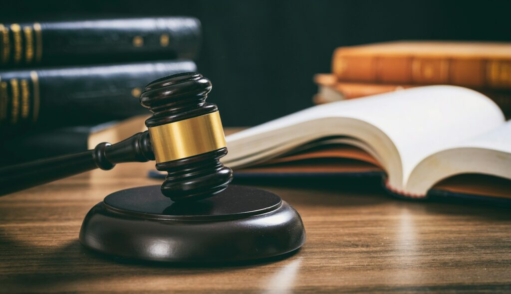 Judge gavel on a wooden desk, law books background